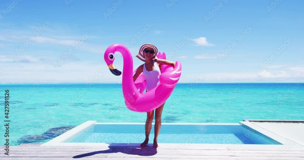 Vacation travel fun. Funny woman dancing happy and cheerful and funny with flamingo swimming pool float around waist excited of tropical hotel holiday getaway