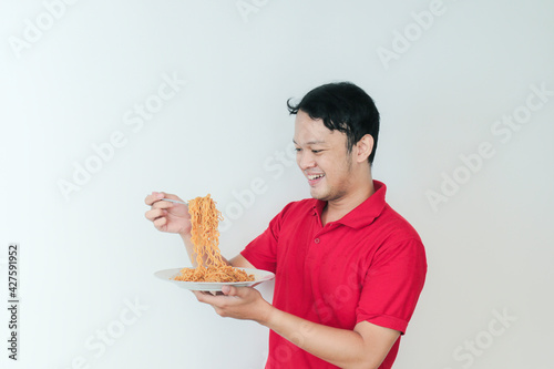 Portrait of happy Young Asian man enjoys noodles. Eating lunch concept.