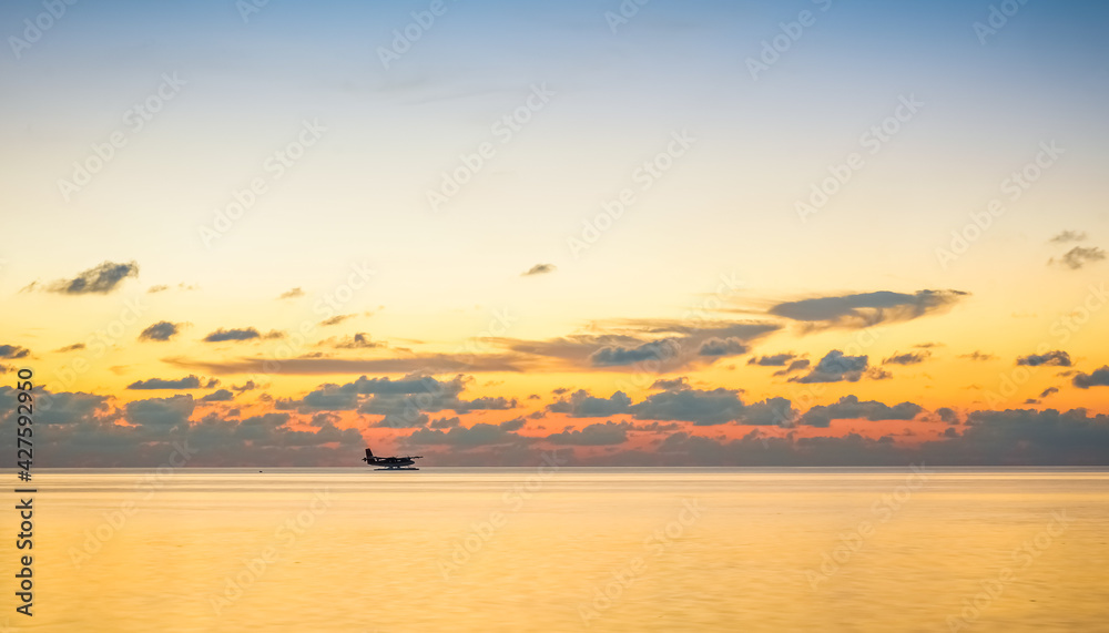 landing of a seaplane on the maldivian lagoon at sunset. luxurious travel concept