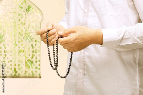 Muslim man praying with prayer beads on his hands