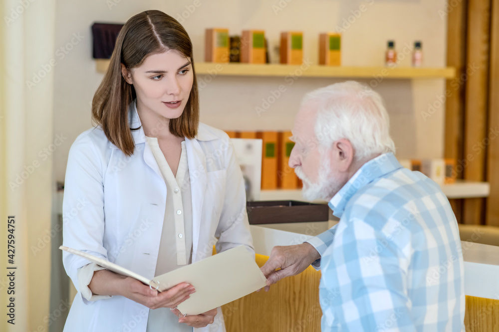 Obraz premium Young shop assistant in perfume shop showing a new fragrance to a mature customer