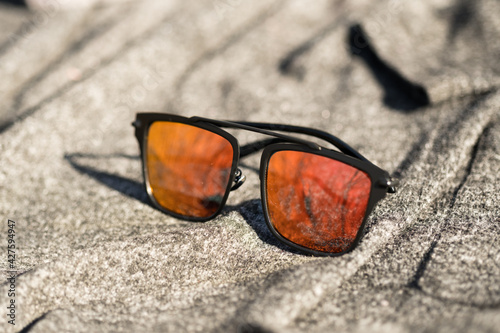 Futuristic sunglasses design with big red flat lenses closeup shoot outside in a summer day . Selective focus. High quality photo