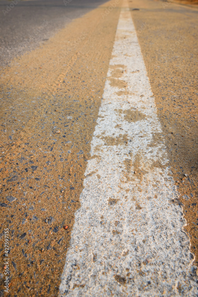 Obraz premium Closeup empty asphalt road with sand and white marking line for given direction. Abstract adventure background concept and transportation idea