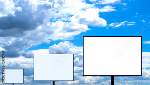 Three blank billboards stand in a row against a cloudy sky.