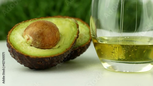 Pours avocado oil into a glass next to the avocado. 4K video close-up of healthy food.
 photo