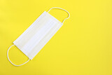 White medical protective mask isolated on yellow background. 