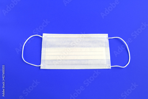 White medical protective mask isolated on blue background.