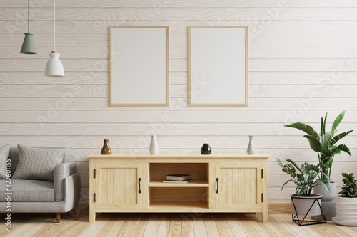 Living room with a picture frame on a white wooden wall, with hanging lamps, decorated with wooden cabinets, sofas and plants.3d rendering.