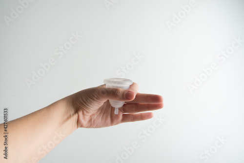 hand is holding menstrual cup on white background