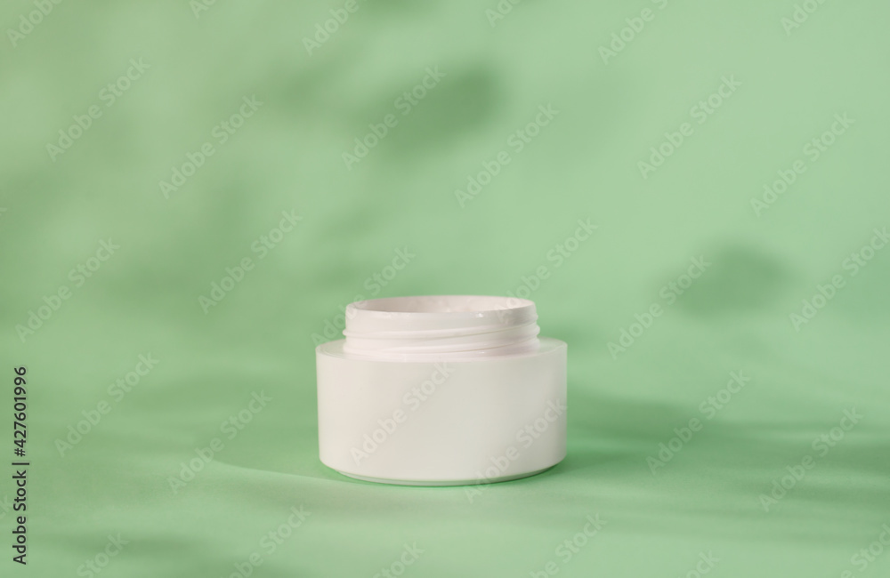 White moisturizer cream, shadow play on white background. Cream container mockup on mint background. Blank Cosmetics jar, packaging design. Skincare and body care concept. White moisturizer cream, shadow play on white background. Cream container mockup on mint background. Blank Cosmetics jar, packaging design. Skincare and body care concept.