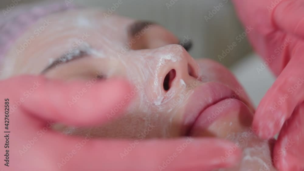 Professional beautician rubbing liquid cream on the face. Professional beautician rubbing liquid cream on the face.