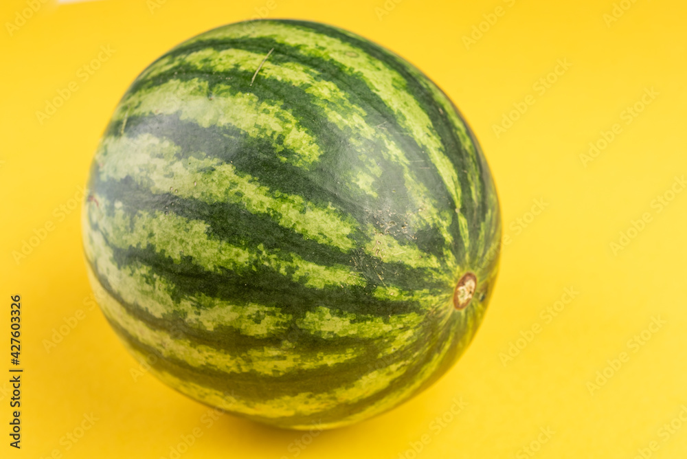 Green watermelon on yellow background side view Green watermelon on yellow background side view