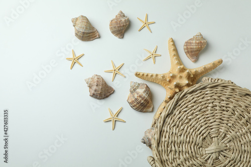 Straw bag and seashells on white background