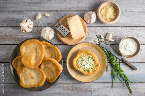 Traditional Hungarian Langos with garlic, cheese and sour cream, garnished with chopped chives shot top view