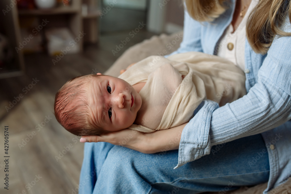 Fototapeta premium Little newborn baby boy in mom's arms at home 