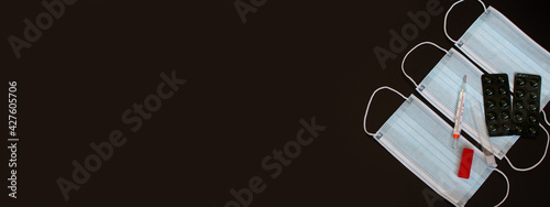 Banner - medical masks, medical thermometer, pills in a blister. On a black background.