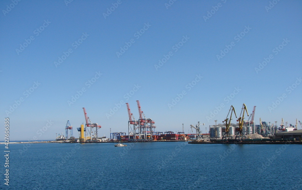 View from the sea station on the coastal cargo port surrounded by a calm surface of the blue sea.