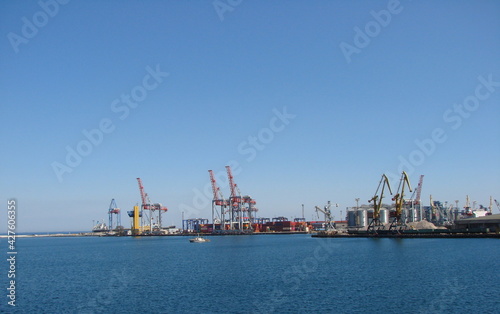 View from the sea station on the coastal cargo port surrounded by a calm surface of the blue sea.