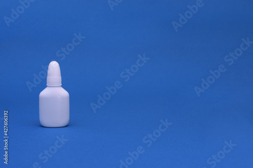 Nasal spray close-up on a blue background. Medicine for the treatment of runny nose, allergies. copy space