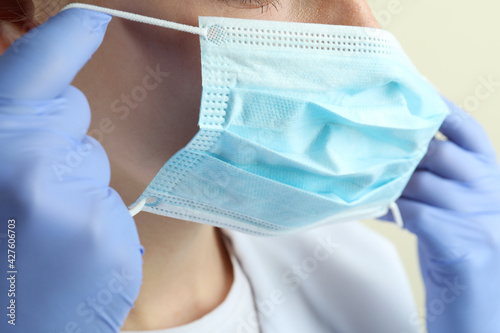 Female doctor puts on a mask, close up