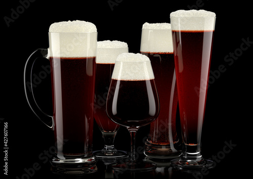 Set of fresh draft beer glasses with bubble froth isolated on black background.