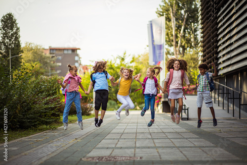 Group of elementary age schoolchildren jumping in schoolyard. photo