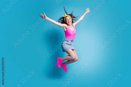 Full size photo of young excited girl happy positive smile crazy have fun jump up isolated over blue color background