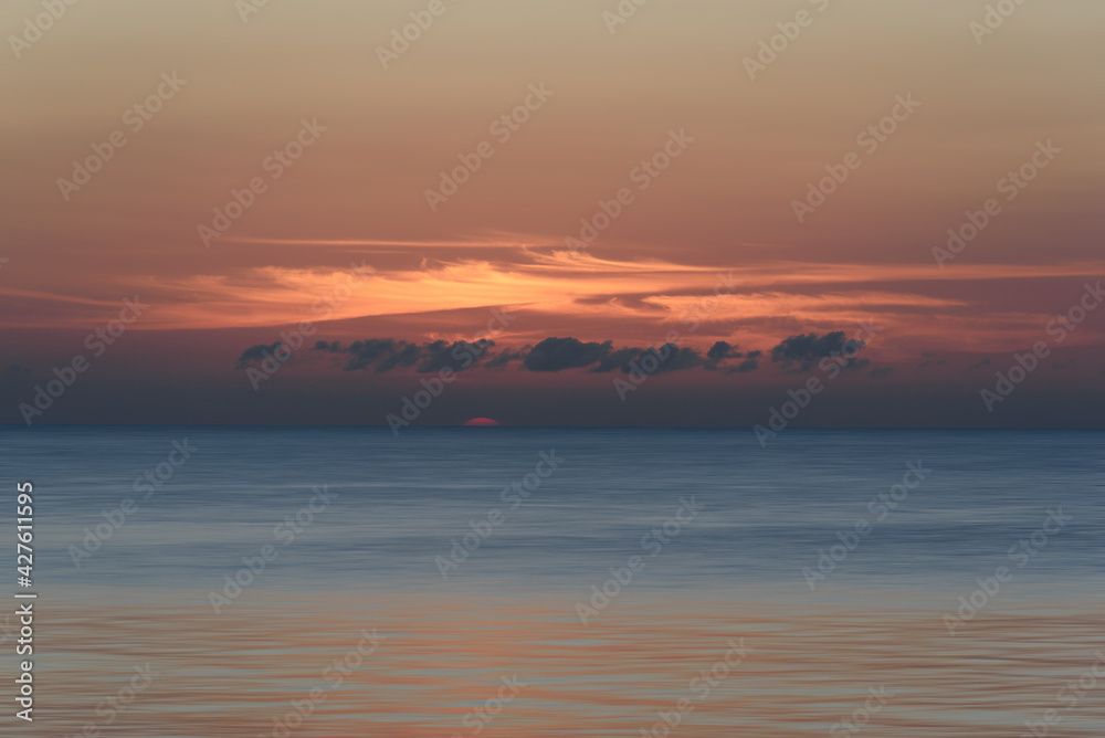 sunset at the ocean with cloudy orange sky