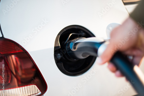 Man pours fuel into his car. Focus is on hand. Electric pump for car.