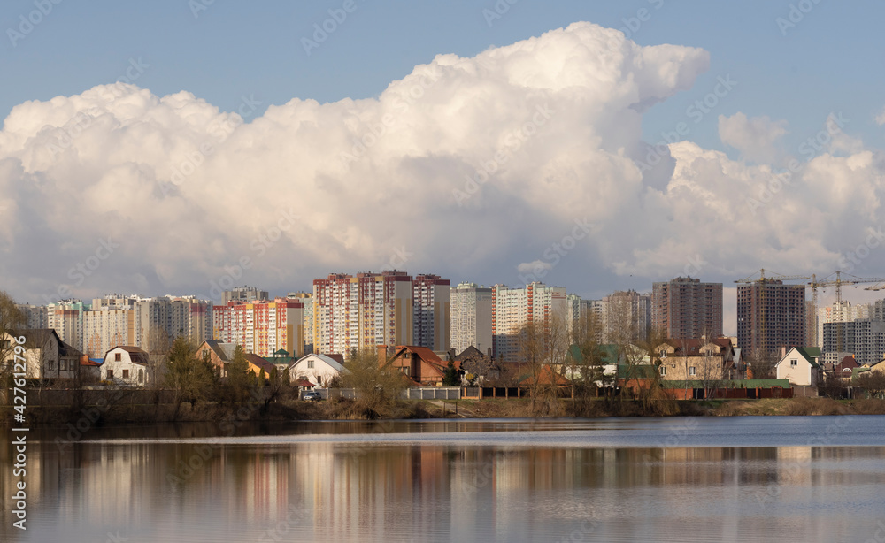 View on a sunny day from the shore of the lake to residential buildings in the city.

