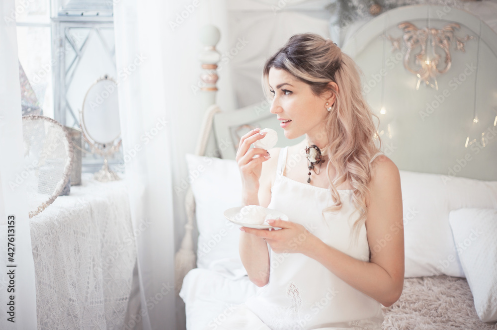 Cute young woman eating sweets in the morning in the bedroom. Gentle winter morning. Cute young woman eating sweets in the morning in the bedroom. Gentle winter morning.