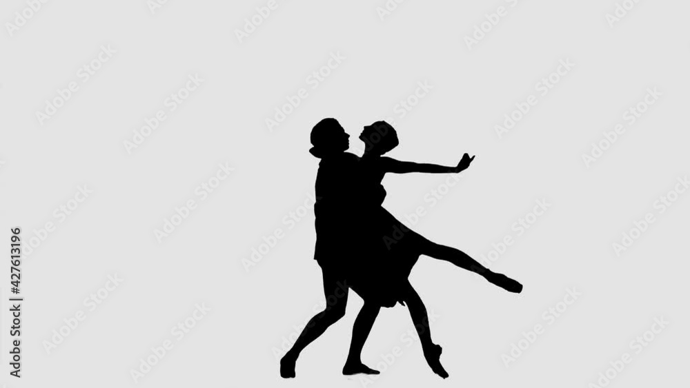 Silhouette professional ballet pair practicing moves on dark stage. Gracefulness and tenderness in every movement. Silhouette professional ballet pair practicing moves on dark stage. Gracefulness and tenderness in every movement.