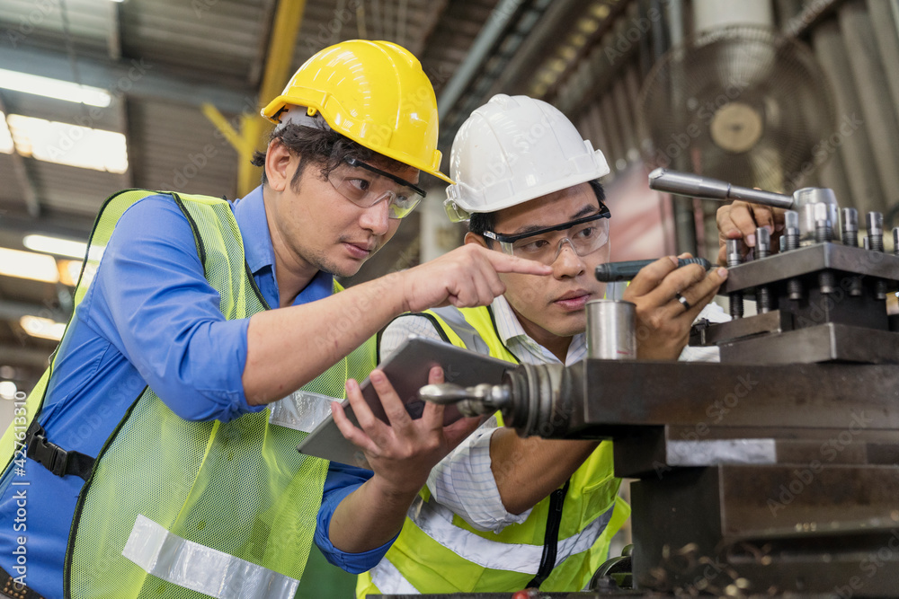 Handsome engineer in a factory. Professional technicians are holding a tablet to control work in industrial plants. Handsome engineer in a factory. Professional technicians are holding a tablet to control work in industrial plants.