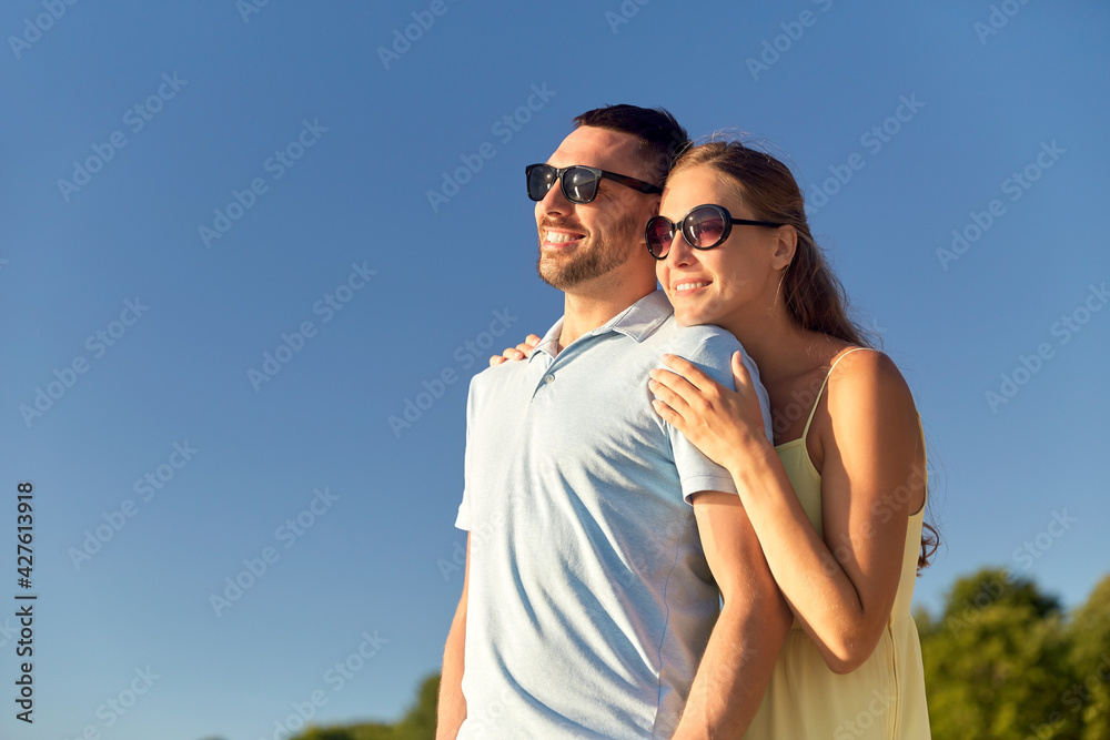 leisure, relationships and people concept - happy couple in sunglasses hugging outdoors in summer