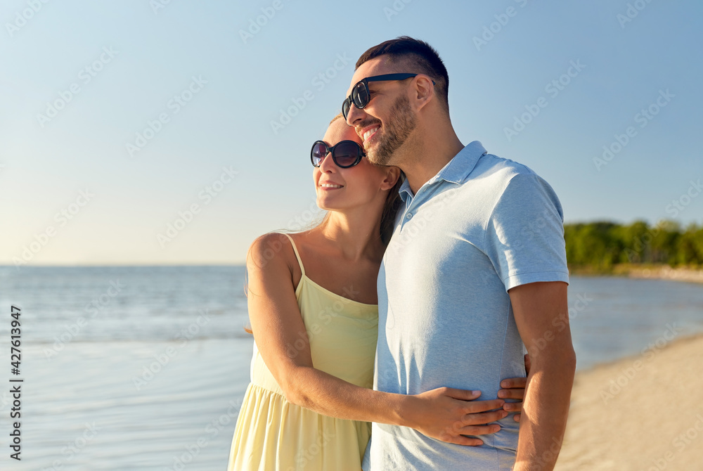 leisure, relationships and people concept - happy couple in sunglasses hugging on summer beach