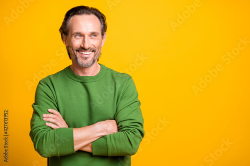 Photo of interested guy crossed hands look side empty space white smile wear green sweater isolated yellow color background