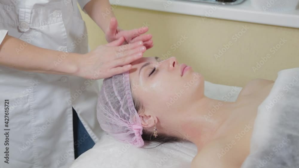 Professional beautician rubs liquid soap on a woman's face. Professional beautician rubs liquid soap on a woman's face.