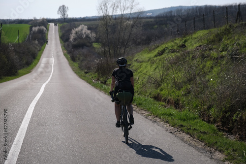 Bike packing cyclist riding on a empty paved road in springtime