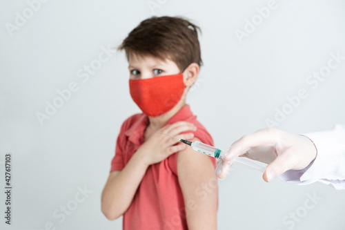 Banner. A child in a medical mask is vaccinated against the coronavirus in the covid pandemic. Doctor in gloves with a syringe makes an injection. photo