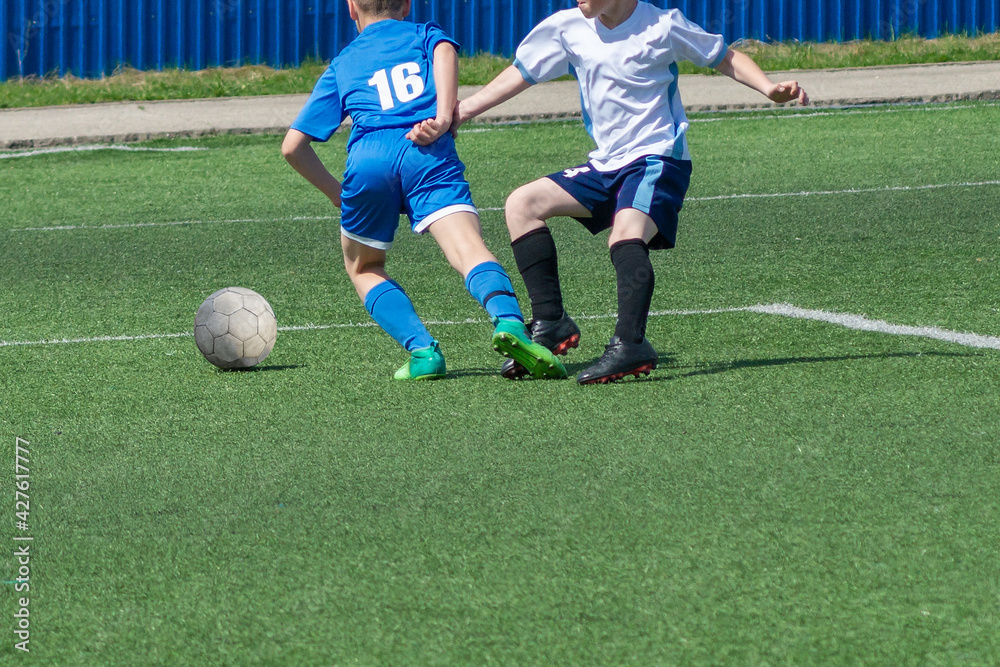 Children's football. An interesting football moment at the match and training. The active struggle and dynamics of the boys' soccer match. The boys are recklessly fighting for the ball