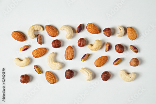 Different types of nuts scattered on isolated white background. Nutrient dense vegan snacks. Clean eating concept. Close up, copy space for text, top view, flat lay.