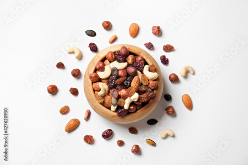 Different types of nuts in a wooden bowl and scattered on isolated white background. Nutrient dense vegan snacks. Clean eating concept. Close up, copy space for text, top view, flat lay.