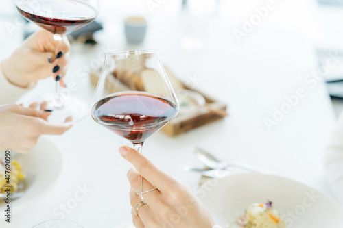 Person holding a glass of wine. Woman drinking red wine, saying cheers in a bar or restaurant