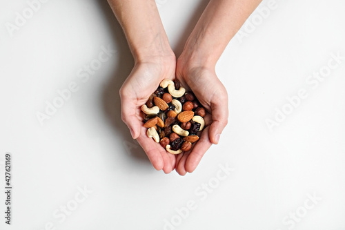 Fotografie Cropped shot of woman's hands holding a pile of mixed nuts and dried berries over isolated white background