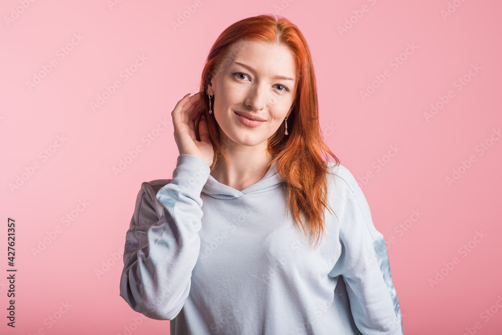 Beautiful young redhead girl in the studio on a pink background Beautiful young redhead girl in the studio on a pink background