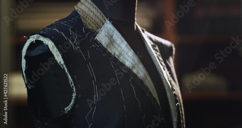 Close up of custom made high quality tailored suit by designer on tailor mannequin in luxury tailoring atelier.  Concept of fashion, handmade, hand craft, couturier and business.