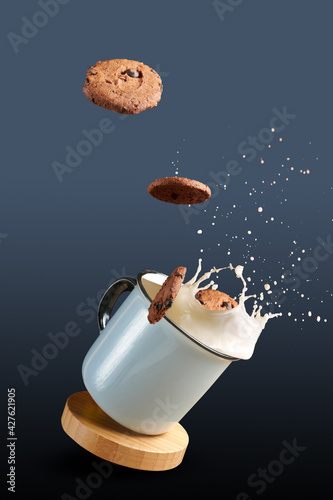 cookies are dipped in milk. cookies in the air flying into the milk. splash of milk in a cup