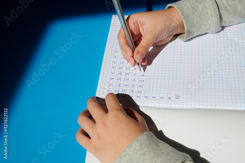 children's hands close up write in a notebook. the child does homework at home in quarantine