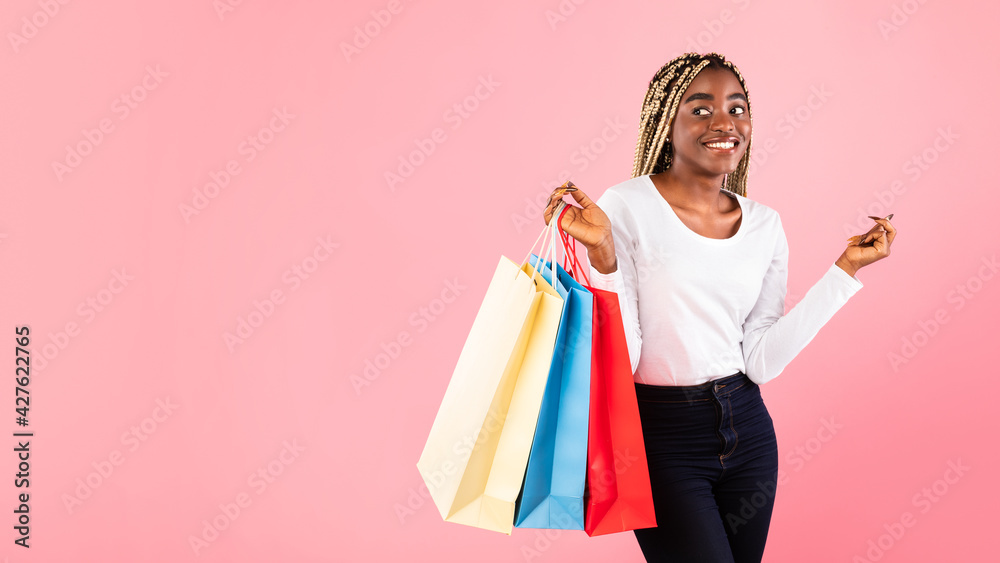 Fototapeta premium Black lady holding shopping bags at pink studio wall