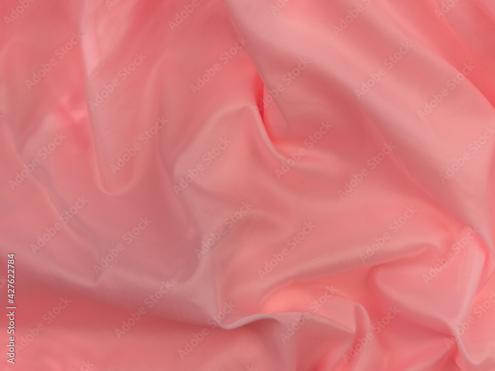 Fototapeta premium Pink silk fabric texture top view. Red coral glossy satin background. Fashion color feminine clothes trend. Female blog backdrop text sign design.Girly abstract wallpaper smooth textile surface.